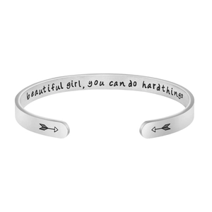 Détail de la citation gravée et des flèches sur le bracelet jonc en acier inoxydable