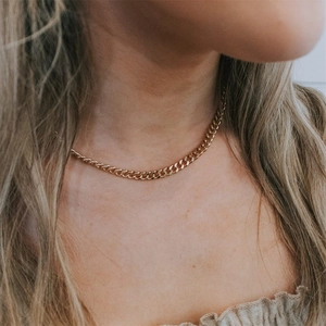 Primo piano di una collana a catena groumette placcata oro 14K su una modella elegante