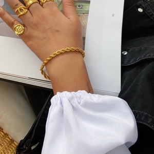 Détail d'un bracelet en chaîne torsadée plaqué or 14K et d'un ensemble de bagues empilées