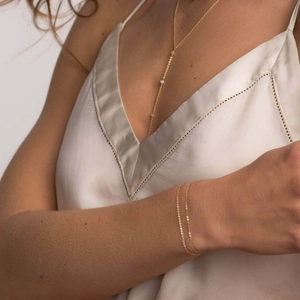 Minimalist gold necklace with small pearls and layered bracelet on a model
