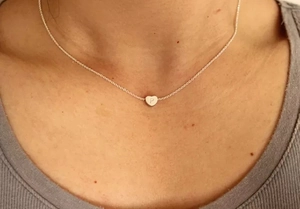 Gros plan du collier cœur en argent avec gravure de la lettre P sur un modèle