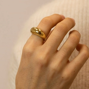 Close-up of a chunky minimalist gold dome ring with a mirror polished finish on model's finger