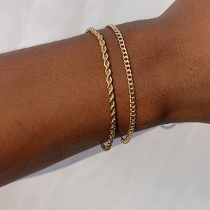 Λεπτομέρεια από χρυσά βραχιόλια με στρώσεις από σχοινί και επίπεδους κρίκους