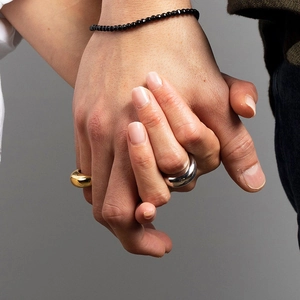 Close-up of minimalist gold and silver dome rings worn by models in a matching pair style
