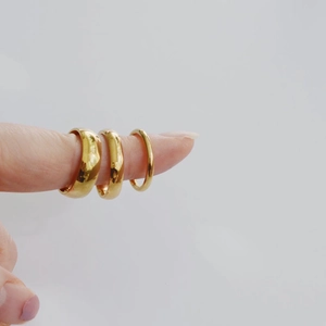 Detailed view of three polished 14K gold-plated stainless steel rings in varying widths