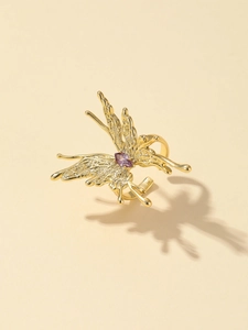 Makro-Detail des goldenen Schmetterlingsrings mit lila Edelstein und flüssiger Metallstruktur