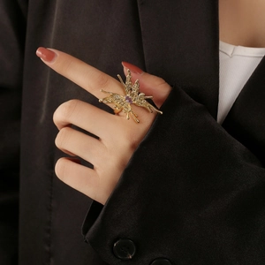 Goldener 3D-Schmetterlingsring mit lila Edelstein auf dem Finger vor schwarzem Anzug