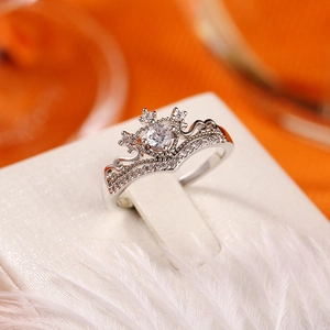 Dettaglio macro dell'anello a corona in zircone con incastonatura micro-pave su pelle bianca