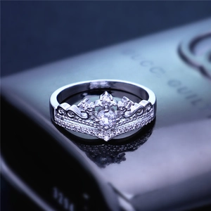 Elegante anello a corona con zircone e pietra centrale su superficie riflettente
