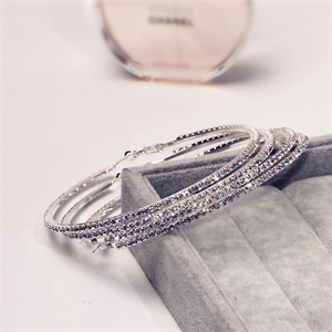 Vue macro de grandes créoles argentées avec strass brillants sur boîte à bijoux