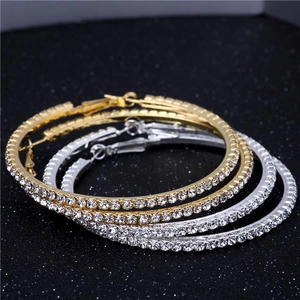 Gros plan de boucles d'oreilles créoles dorées et argentées avec strass blancs brillants