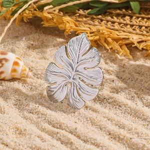Elegante zilveren roestvrijstalen monstera blad ring op een natuurlijk strand achtergrond