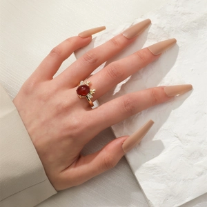 Detail of elegant gold ring with red oval gemstone and dainty zircon antlers