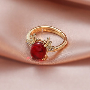Detailed macro view of gold deer antler ring with large red oval stone on pink silk