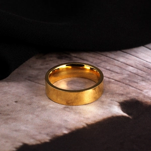 Detailopname van een gepolijste goudkleurige titaniumstalen ring met plat minimalistisch design