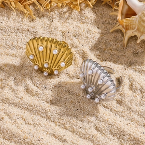 Anelli a conchiglia regolabili in oro e argento con perle su sfondo di sabbia marina