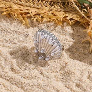 Anello a conchiglia in acciaio inossidabile con perle bianche su sfondo spiaggia