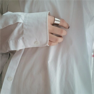 Primo piano di un ampio anello minimalista in acciaio inossidabile indossato sull'indice
