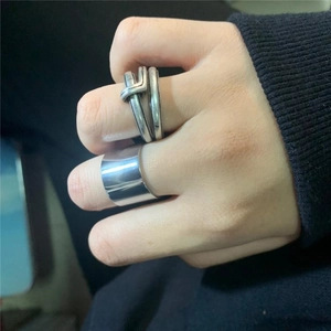 Dettaglio macro di anello largo piatto e anello a treccia in argento su maglia nera