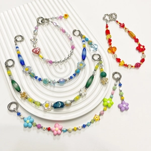 Bijoux de téléphone faits main en perles colorées avec fleurs sur plateau blanc