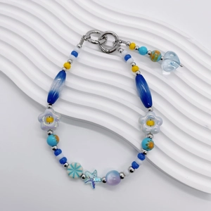 Détail d'une dragonne de téléphone en perles avec étoiles de mer bleues et fleurs nacrées