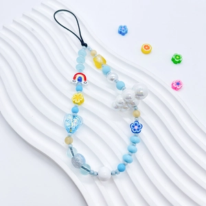 Macro detail of handmade beaded phone strap with cloud charm and floral resin beads