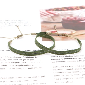 Detail of army green woven bracelets with adjustable cord and silver stitching pattern