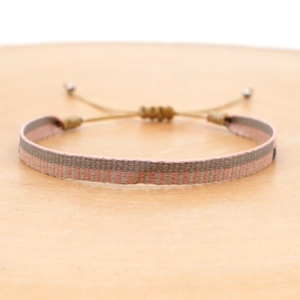 Close-up of pink and grey woven bohemian bracelet with adjustable drawstring closure