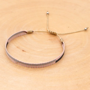 Detailed view of bohemian woven fabric bracelet with pink and beige checkered pattern