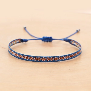 Detail of bohemian woven friendship bracelet with blue and orange geometric patterns