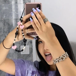 Close-up of Y2K style silver cross ring, chain bracelet and colorful phone charm strap