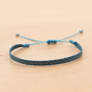 Detail of blue geometric woven bracelet featuring an adjustable drawstring and metal beads