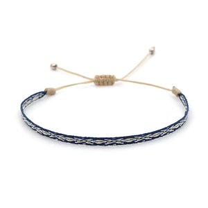 Detailaufnahme von handgewebtem Armband mit marineblauen Ethno-Mustern und verstellbarem Knoten