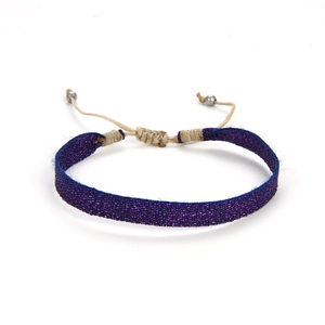 Detail van geweven bordeauxrode armband met verstelbare veters en metalen kralen