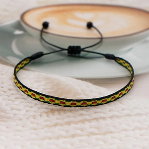 Detailed view of handmade woven ethnic bracelet with adjustable sliding knot on soft fabric