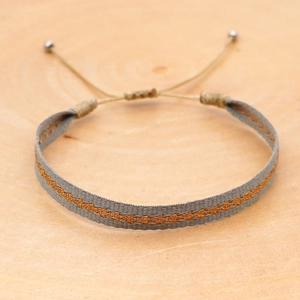 Detail of woven Bohemian bracelet with orange geometric embroidery and silver bead closure