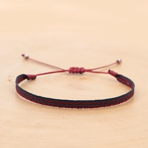 Detailed view of handmade woven bohemian wristband with red and black herringbone pattern
