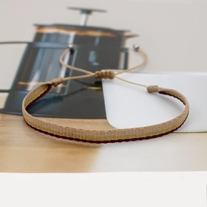 Detail of bohemian woven bracelet in khaki and gold with adjustable drawstring