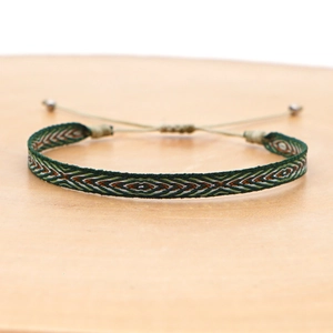 Close-up of bohemian hand-woven bracelet with green and orange geometric diamond patterns