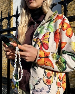 Close-up of colorful crystal bead phone strap held against a white fleece butterfly jacket