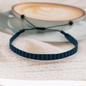 Close-up of handmade ethnic woven bracelet with blue and green stripes on white knit