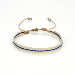 Detail van een handgeweven etnische armband met crème en blauwe patronen en koordsluiting