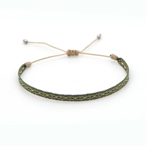 Detail of handmade woven bracelet with olive green and purple geometric diamond patterns