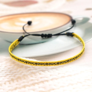 Macro shot of yellow and black ethnic woven friendship bracelet with geometric diamond pattern