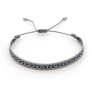 Makroansicht des handgewebten grauen Boho-Armbands mit blau-grünen geometrischen Mustern