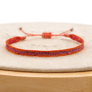 Macro view of woven bohemian friendship bracelet with orange pink waves and adjustable cords