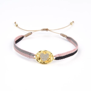 Détail du bracelet tissé à la main avec breloque cœur dorée et sangle rayée colorée