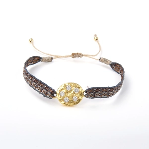 Détail du bracelet tressé bohème avec pièce centrale dorée martelée et micro-incrustations