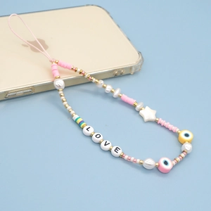 Détail de la lanière de téléphone faite main avec disques en argile rose et fausses perles