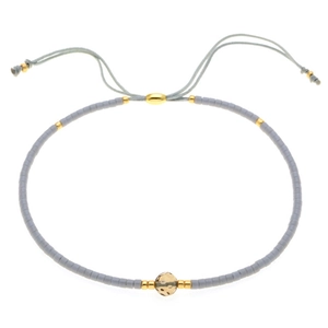 Dettaglio del bracciale con perline blu, perla dorata martellata e chiusura a cordoncino